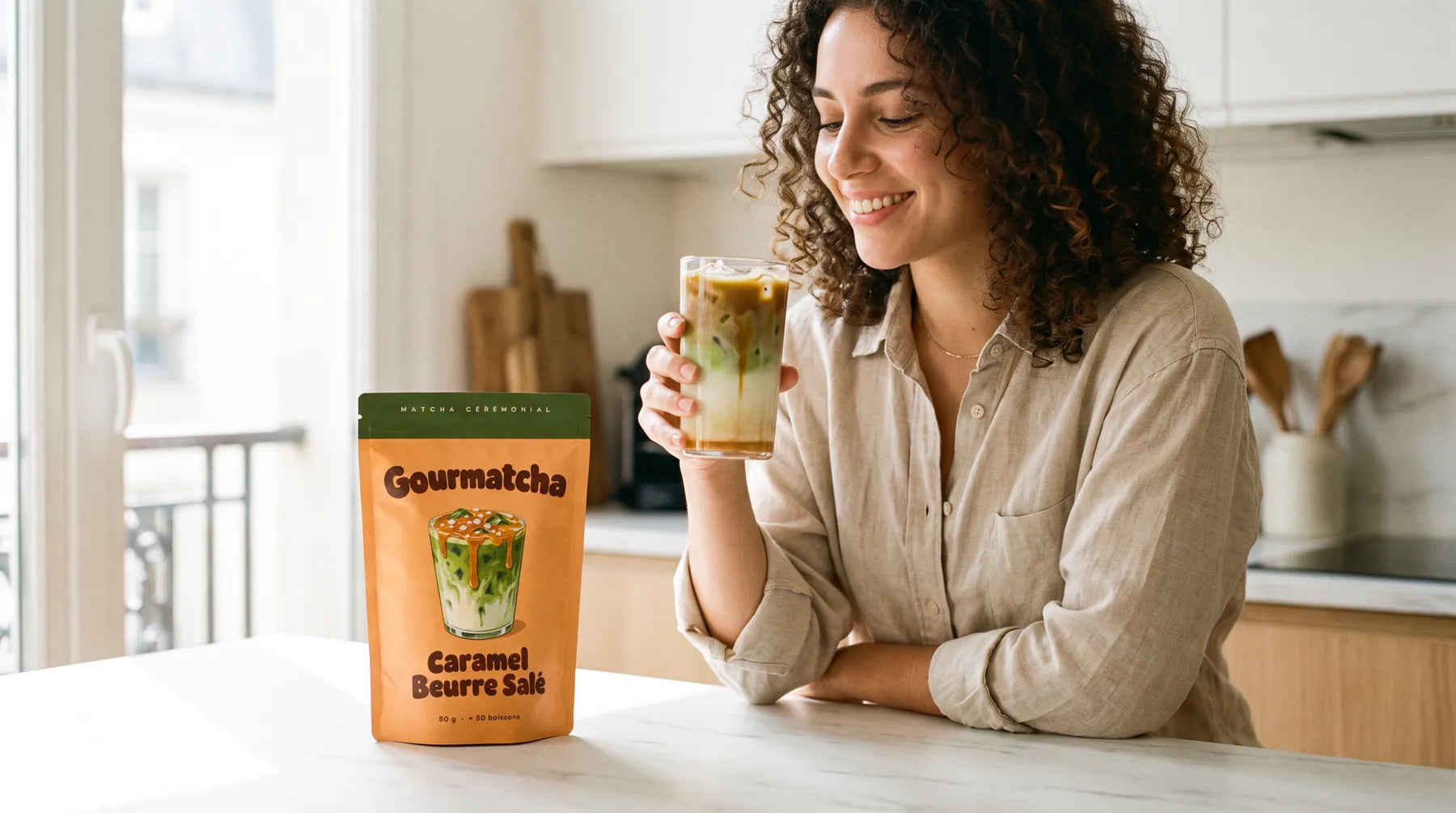Une femme savoure un iced matcha latte Gourmatcha dans sa cuisine